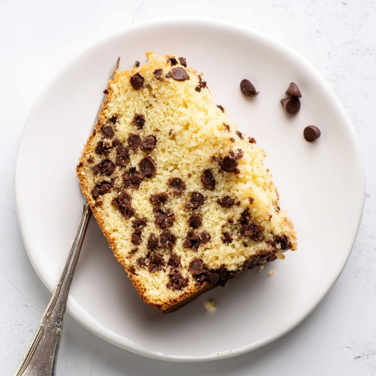 Moist chocolate chip cake loaf with chocolate chunks peeking through the golden brown surface