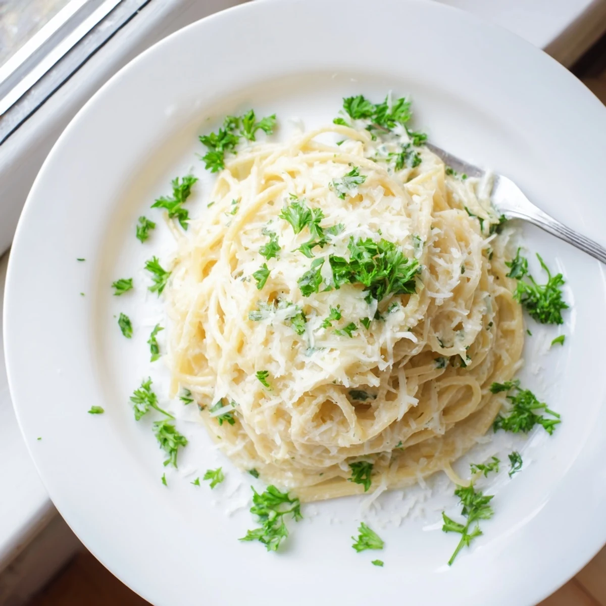 Golden spaghetti coated in a rich, white cheesy garlic parmesan sauce with fresh parsley garnish.