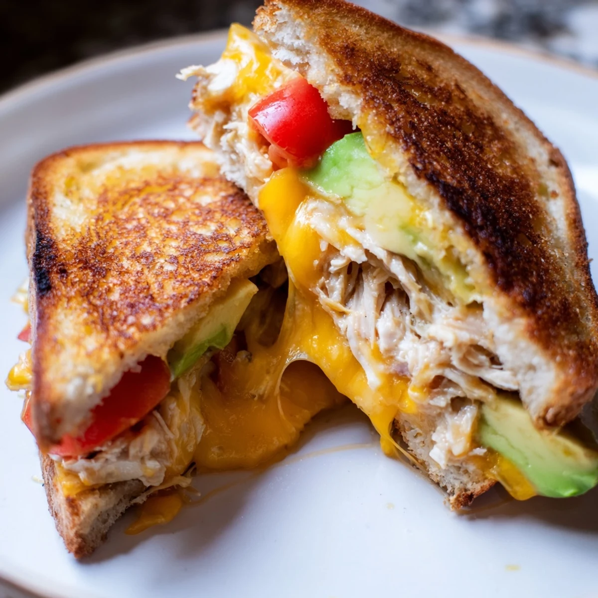 Toasted sourdough chicken avocado melt sandwich layered with creamy avocado and cheddar cheese