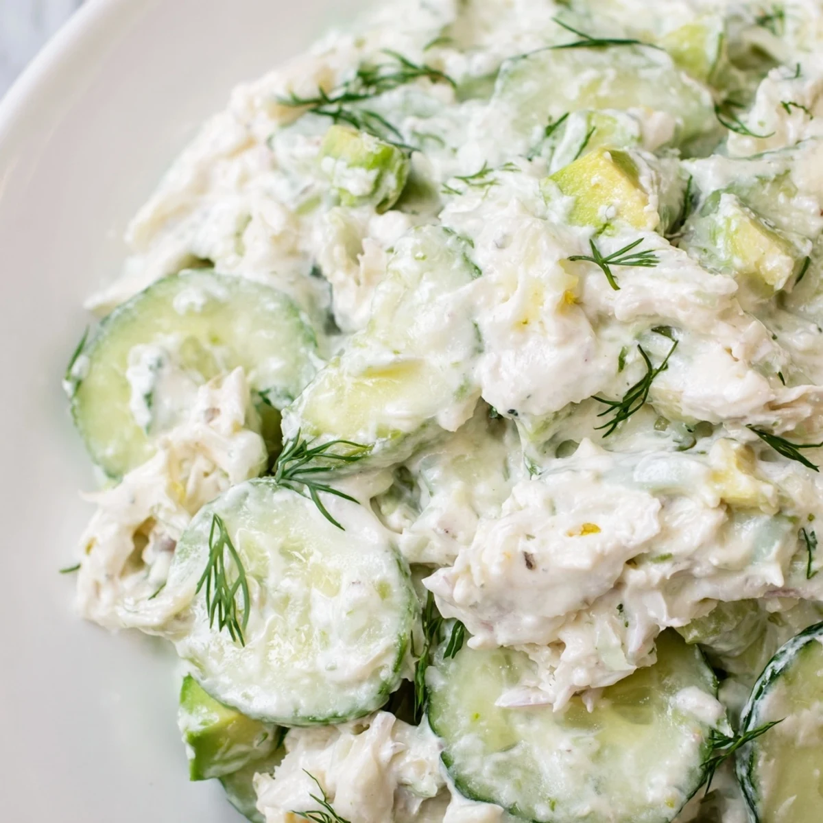 Cucumber salad with crab meat in creamy dressing, garnished with fresh dill and lemon wedges