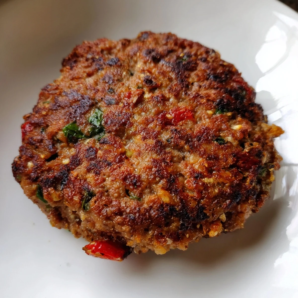 Crispy golden Pakistani Chapli Kabab sizzling in a skillet with aromatic spices and herbs
