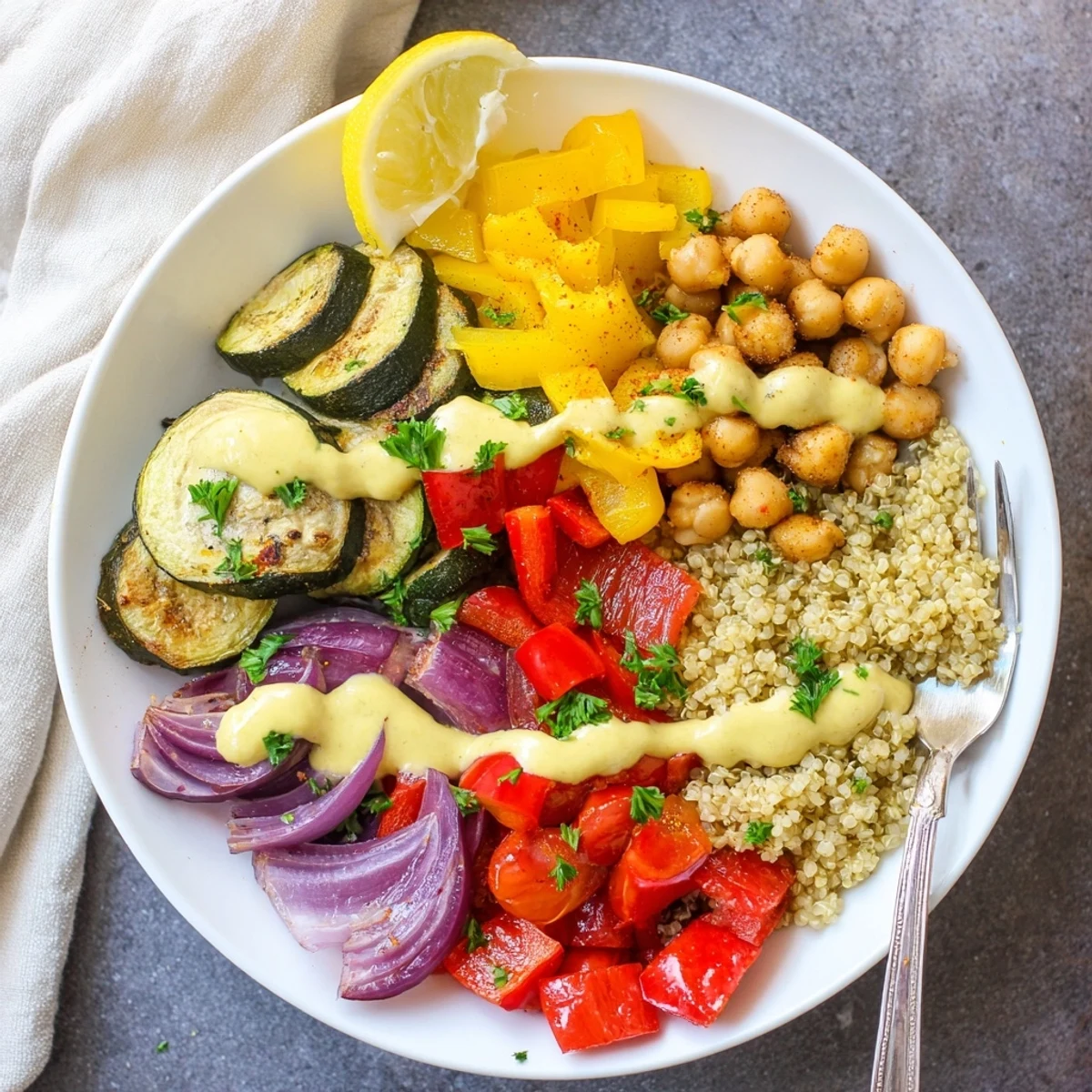Warm vegan Mediterranean roasted vegetables bowl drizzled with creamy tahini-lemon dressing and parsley