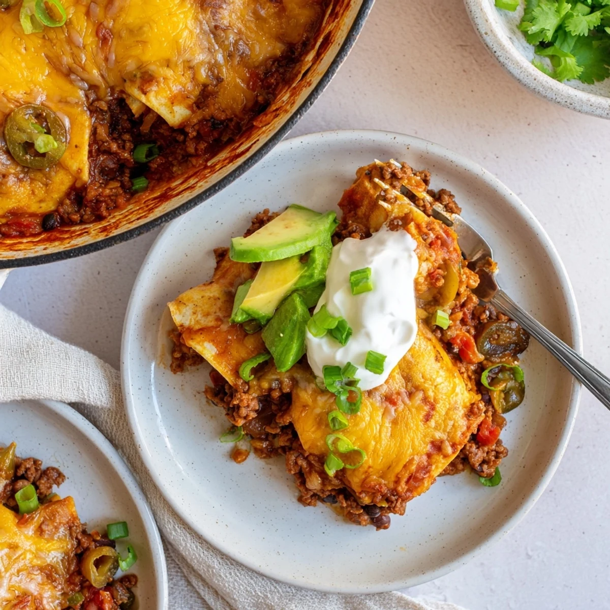 Serve Beef Skillet Enchiladas hot with avocado, sour cream, and green onions