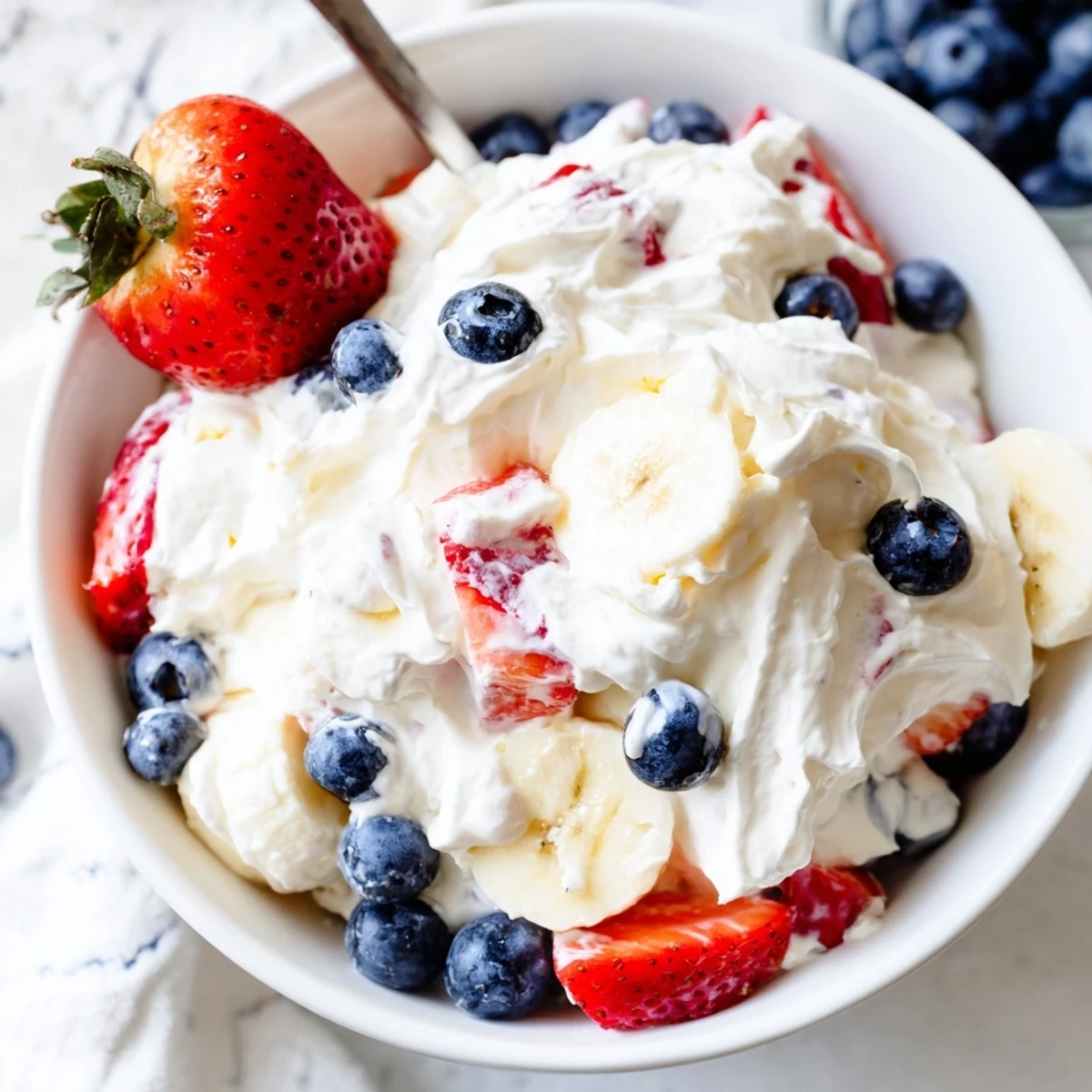 Fluffy Red White And Blue Cheesecake Salad served cold with extra berry garnish.