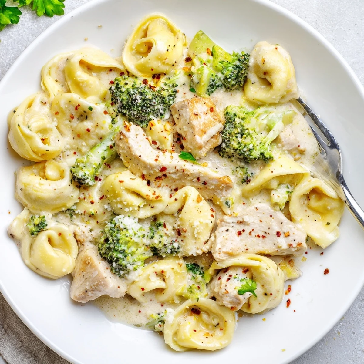 Creamy Garlic Parmesan Tortellini Chicken Broccoli Recipe steaming in skillet, Parmesan melting