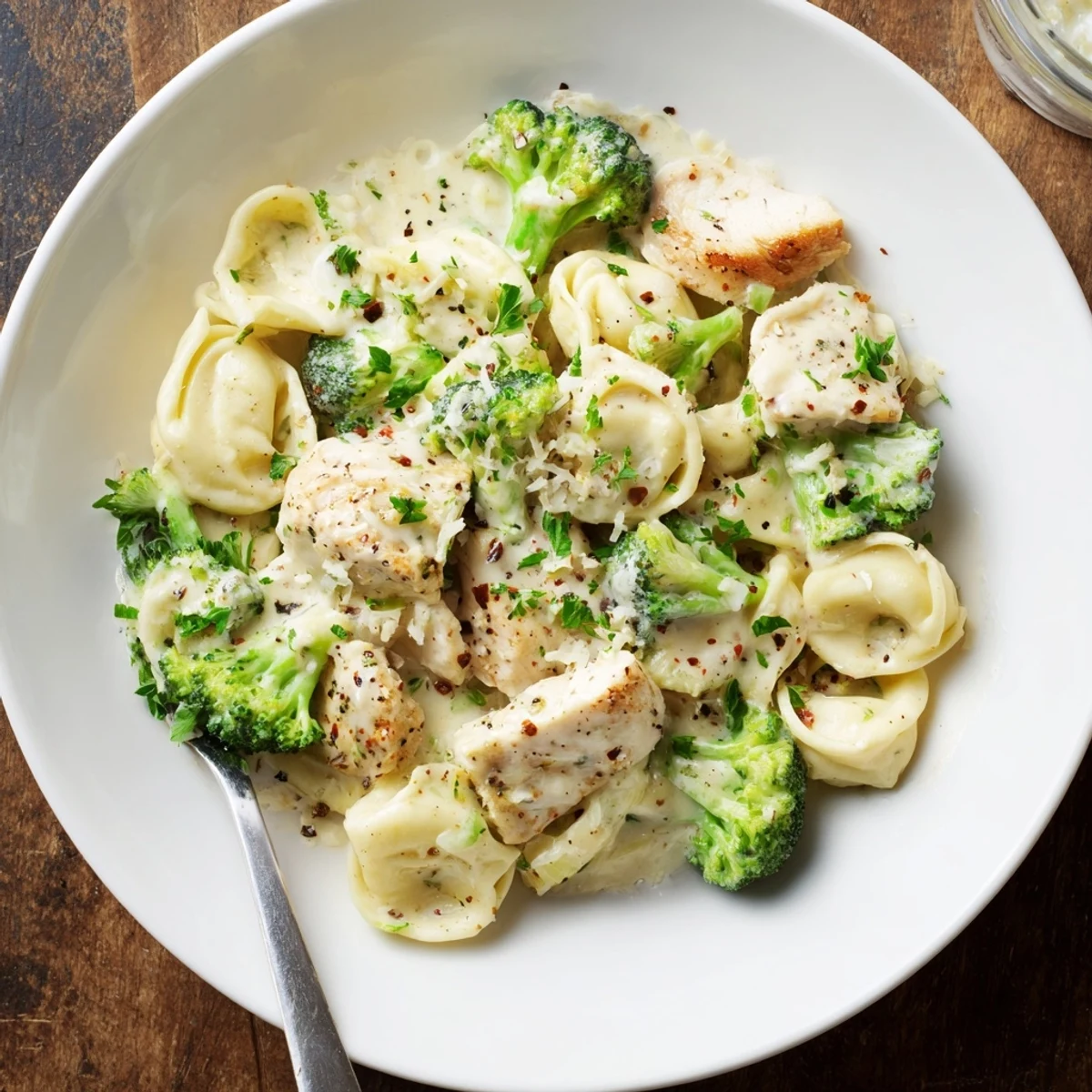 Plate of Creamy Garlic Parmesan Tortellini Chicken Broccoli Recipe garnished with fresh parsley
