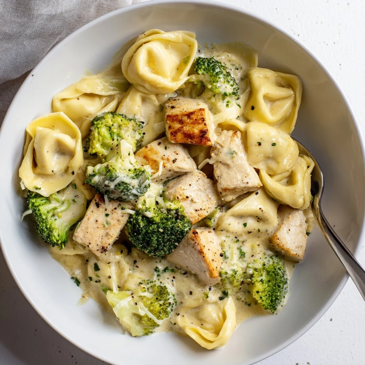 Fork-twirled Creamy Garlic Parmesan Tortellini Chicken Broccoli Recipe with juicy chicken bites
