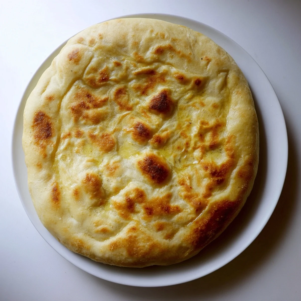 Golden Turkish Bazlama flatbread with pillowy soft interior and lightly charred surface, freshly cooked in a skillet