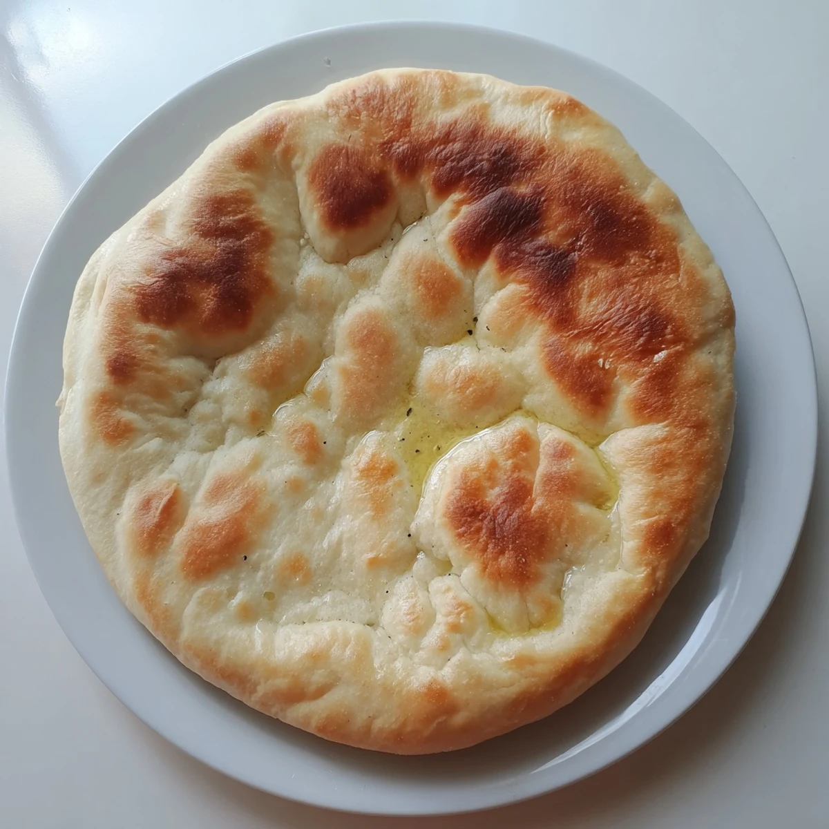 Soft homemade Turkish Bazlama bread displaying golden brown bubbles, perfect for scooping dips or wrapping grilled meats