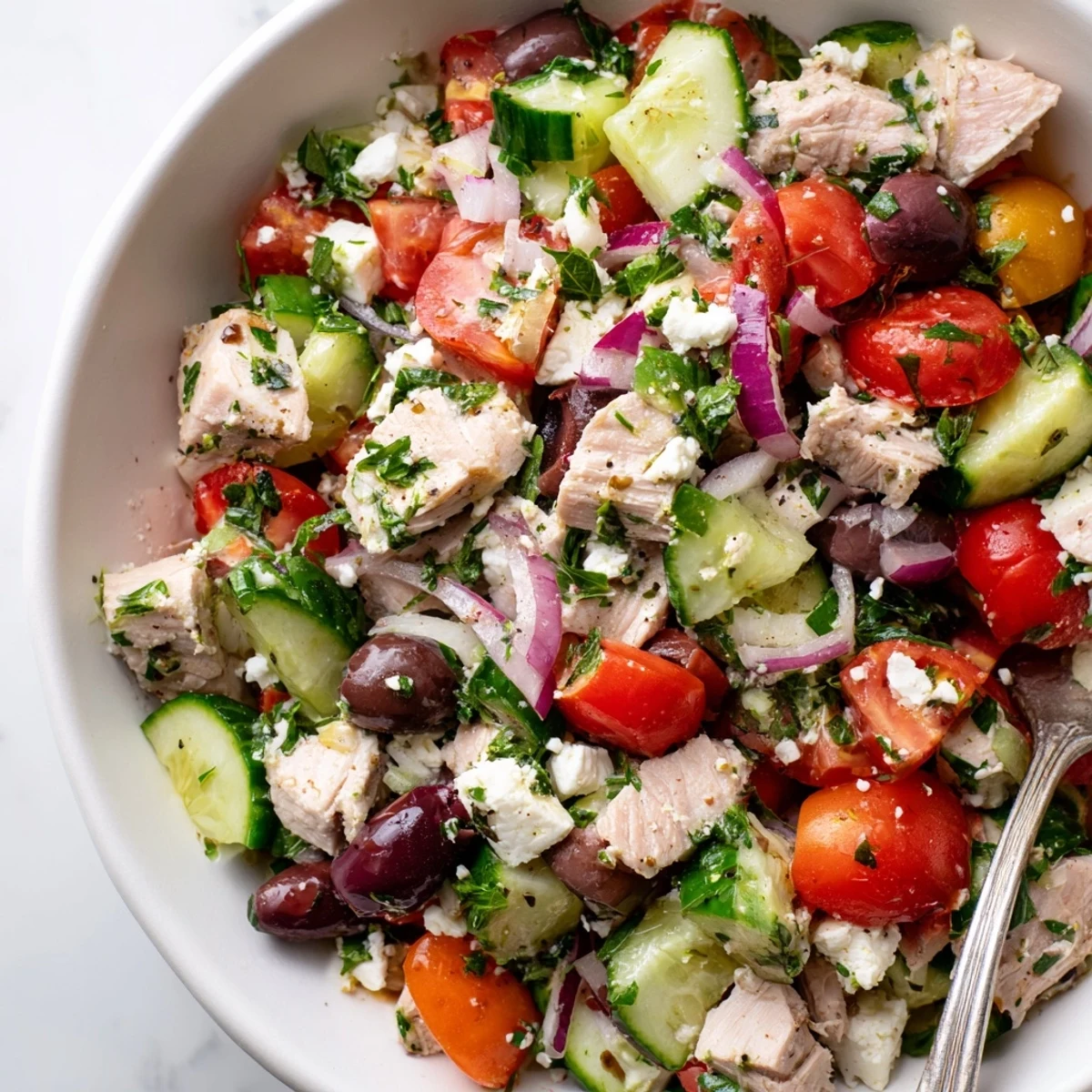 Fresh Mediterranean tuna salad with chunky tuna, crisp vegetables, olives, and tangy lemon dressing in a white bowl