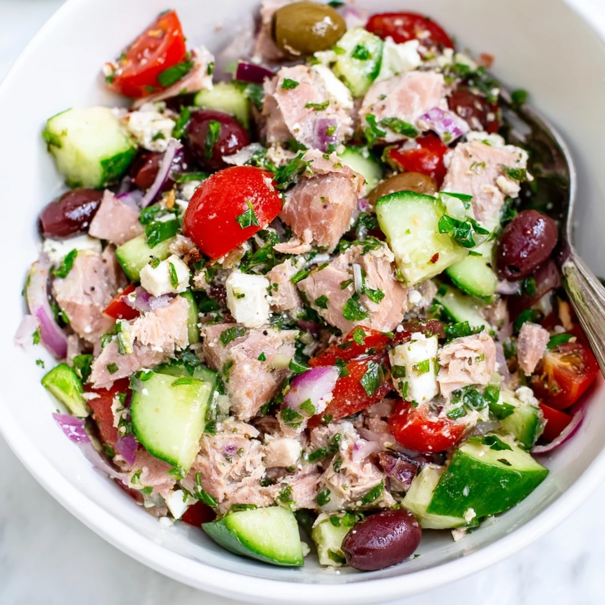 Protein-rich Mediterranean tuna salad tossed with bright vegetables, Kalamata olives, and zesty olive oil dressing on a rustic table