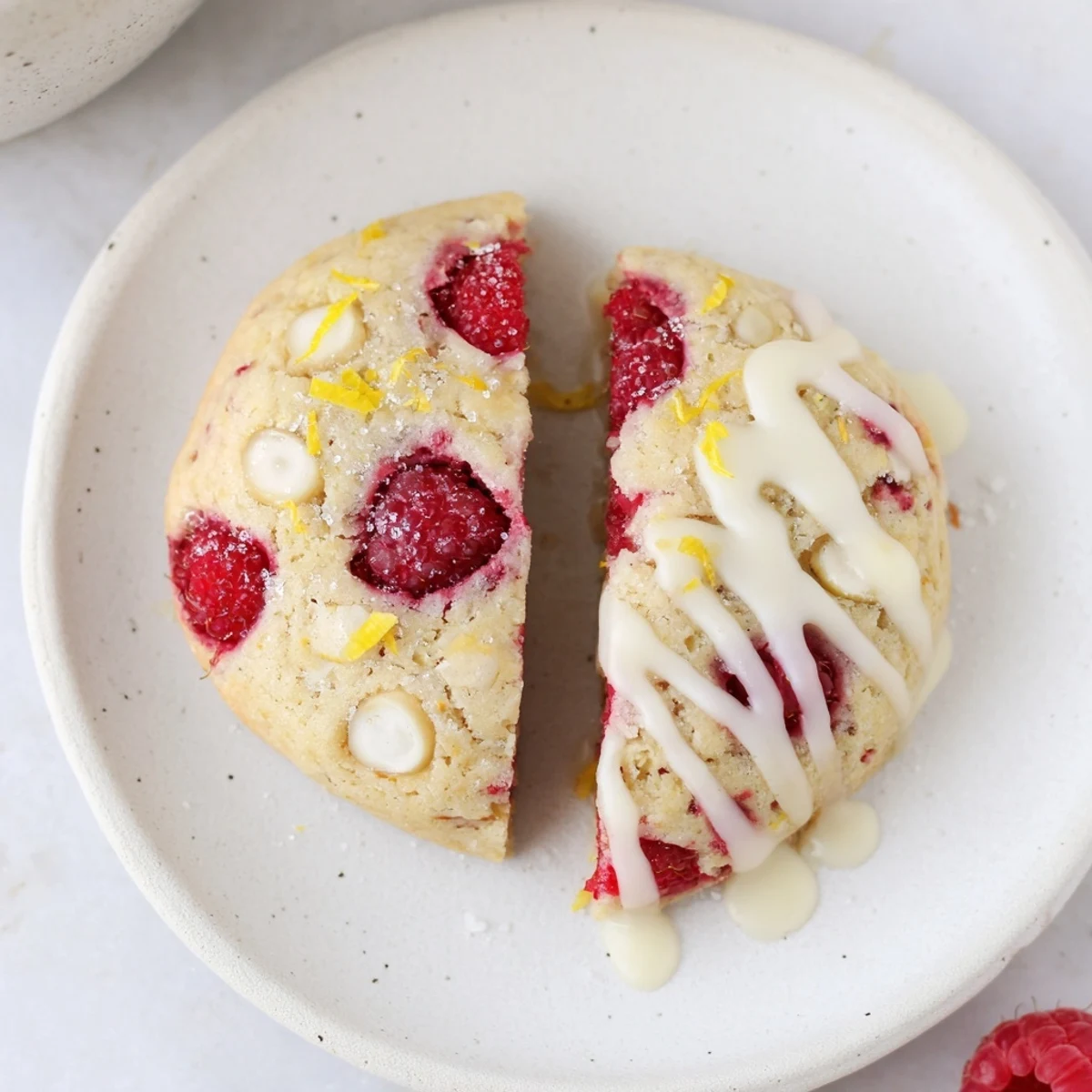 Chewy Lemon Raspberry Cookies on parchment, warm, glossy raspberries and bright lemon zest