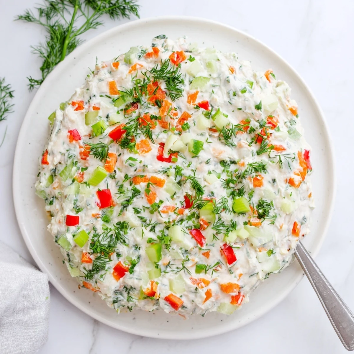 Garden vegetable spread featuring fresh carrots celery and herbs blended into smooth cream cheese