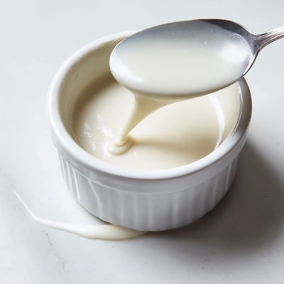 Creamy condensed coconut milk pooling in a mason jar with vanilla bean flecks